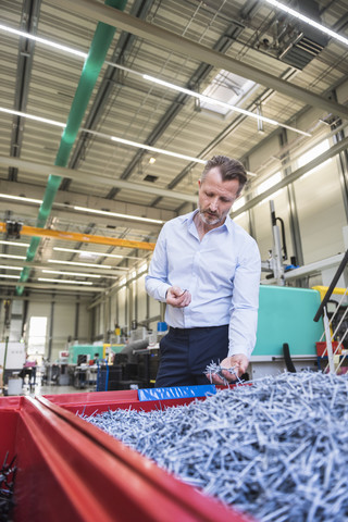 Mann in Fabrik, der Schreddergut im Container untersucht, lizenzfreies Stockfoto