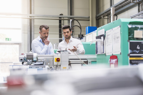 Two men in factory at machine stock photo