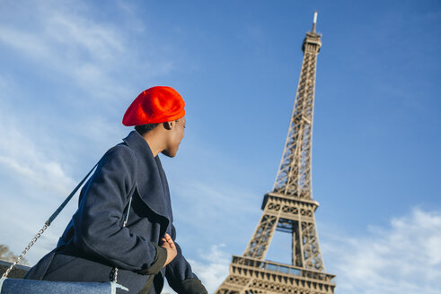 Frankreich, Paris, junge Frau mit roter Baskenmütze vor dem Eiffelturm - KIJF01382