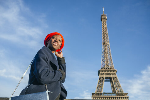 Frankreich, Paris, junge Frau mit roter Baskenmütze vor dem Eiffelturm - KIJF01383