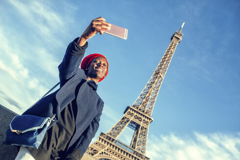 Frankreich, Paris, junge Frau macht Selfie vor dem Eiffelturm - KIJF01384