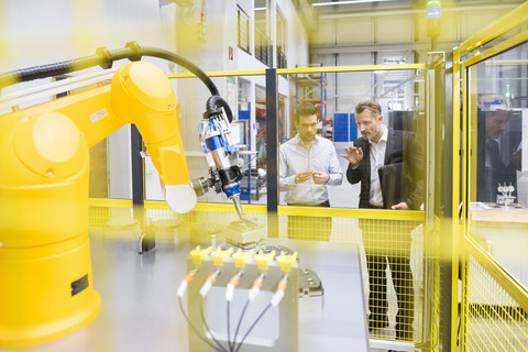 Two businessman observing industrial robots in factory stock photo