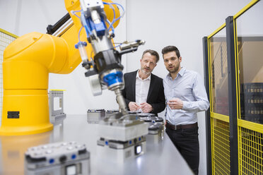 Two businessman observing industrial robots in factory - DIGF02108