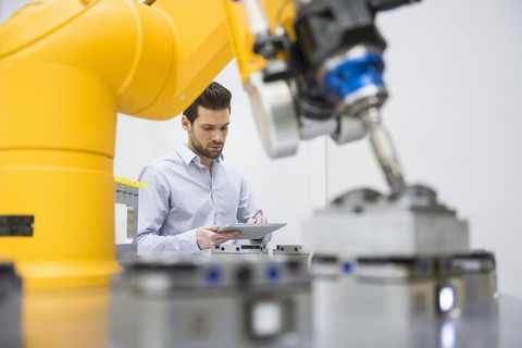 Junger Geschäftsmann bei der Kontrolle der automatisierten Produktion in einer Fabrik, lizenzfreies Stockfoto