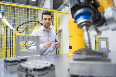 Junger Geschäftsmann bei der Kontrolle der automatisierten Produktion in einer Fabrik - DIGF02118