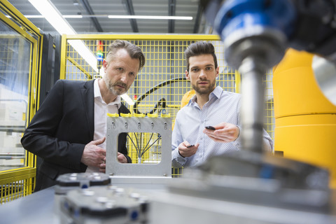 Two businessman observing industrial robots in factory stock photo