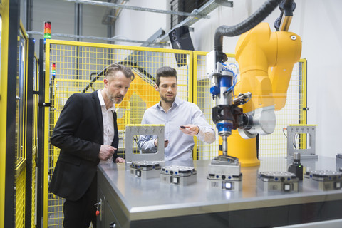 Two businessman observing industrial robots in factory stock photo