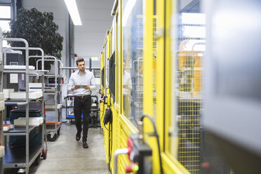 Young businessman checking automated production in factory - DIGF02123