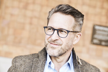 Portrait of smiling man with stubble wearing glasses - FMKF03970