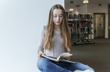 Jugendliches Mädchen liest ein Buch in einer öffentlichen Bibliothek - TCF05378