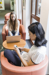 Teenage girl using cell phone in a public library - TCF05380