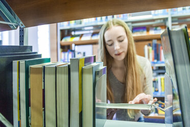 Teenage girl behind bookshelf in a public library - TCF05385