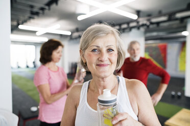 Gruppe von fitten Senioren im Fitnessstudio, die eine Pause machen und eine Erfrischung trinken - HAPF01514