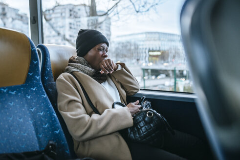 Gähnende junge Frau, die mit dem Bus reist - KIJF01410