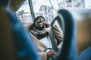Lächelnde junge Frau, die mit dem Bus reist - KIJF01411