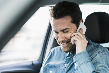 Businessman sitting in car talking on the phone - UUF10345