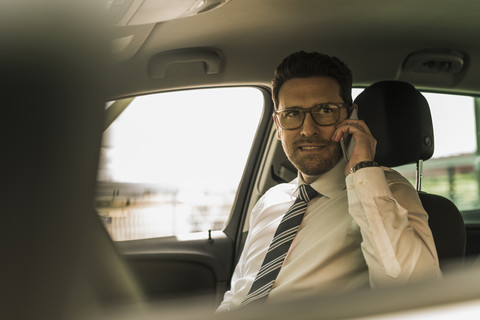 Erfolgreicher Geschäftsmann sitzt im Auto und telefoniert, lizenzfreies Stockfoto