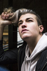 Portrait of daydreaming young man with dyed hair looking up - ABZF01950