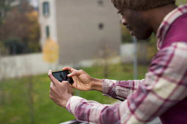 Young man holding cell phone outdoors - MAUF01050