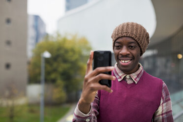 Junger Mann hält Mobiltelefon im Freien - MAUF01052