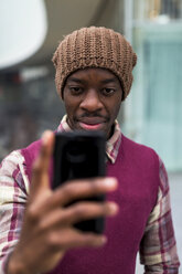 Junger Mann hält Mobiltelefon im Freien - MAUF01053