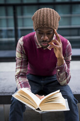 Man sitting on bench reading a book - MAUF01055