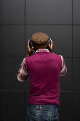 Rückenansicht eines Mannes, der mit Kopfhörern und Mobiltelefon Musik hört - MAUF01061