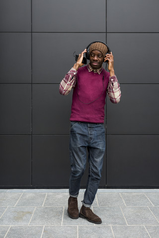 Mann hört Musik mit Kopfhörern und Mobiltelefon, lizenzfreies Stockfoto