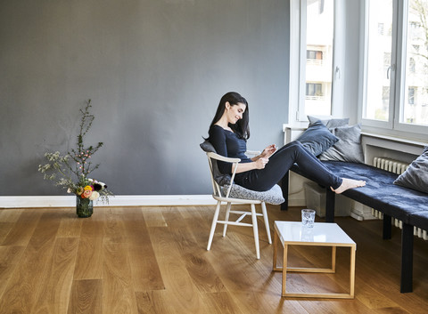 Lächelnde junge Frau, die zu Hause ein Tablet benutzt, lizenzfreies Stockfoto