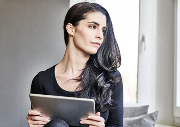 Young woman holding tablet looking sideways - FMKF03998