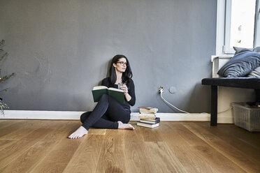 Junge Frau mit Büchern auf dem Boden sitzend - FMKF04006