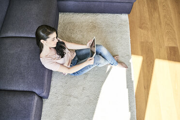 Young woman using tablet at home in living room - FMKF04031