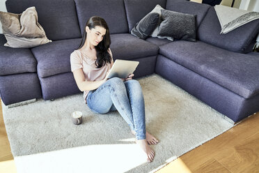 Young woman using tablet at home in living room - FMKF04033