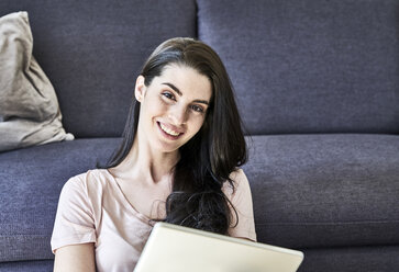 Lächelnde junge Frau mit Tablet zu Hause - FMKF04034