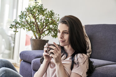 Junge Frau mit Kaffeetasse zu Hause - FMKF04035