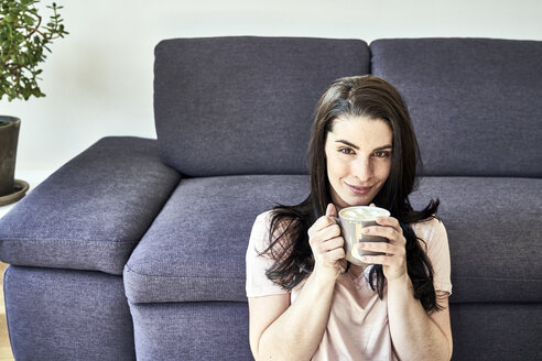 Lächelnde junge Frau mit Kaffeetasse zu Hause - FMKF04037