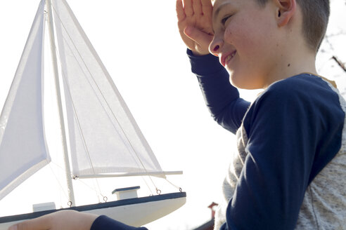 Lächelnder Junge spielt mit Spielzeugboot - ZOCF00208