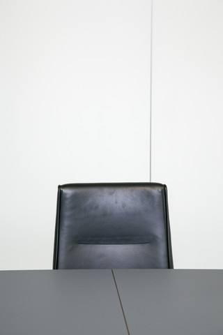 Lederstuhl hinter Tischplatte in einem Büro, lizenzfreies Stockfoto