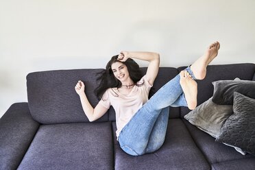 Playful young woman having fun on couch - FMKF04038