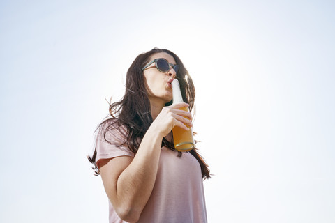 Young woman having a beer under blue sky stock photo