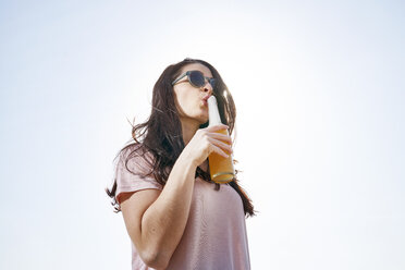 Young woman having a beer under blue sky - FMKF04052