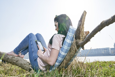 Junge Frau entspannt sich im Freien mit Tablet, lizenzfreies Stockfoto