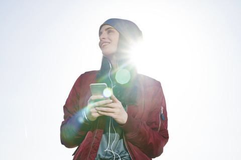 Smiling young woman with cell phone outdoors stock photo