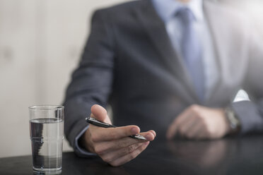 Businessman holding pen next to glass of water - ZEF13591