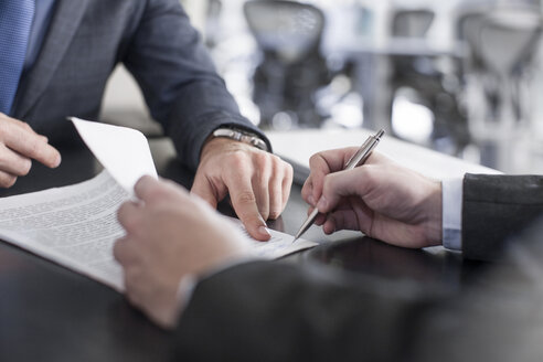 Businessman showing client where to sign document - ZEF13610