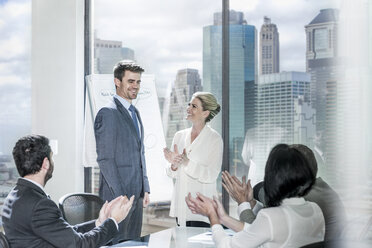 Group of businesspeople clapping hands after a presentation in city office - ZEF13625