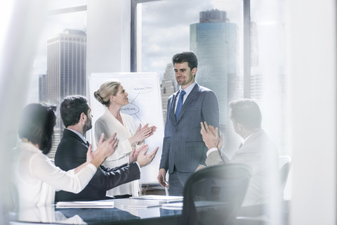 Eine Gruppe von Geschäftsleuten klatscht nach einer Präsentation in einem städtischen Büro in die Hände, lizenzfreies Stockfoto