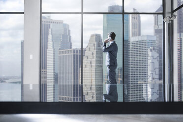 Businessman on the phone in city office looking out of window - ZEF13648