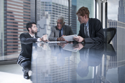 Three businessmen with tablet and documents discussing in office stock photo