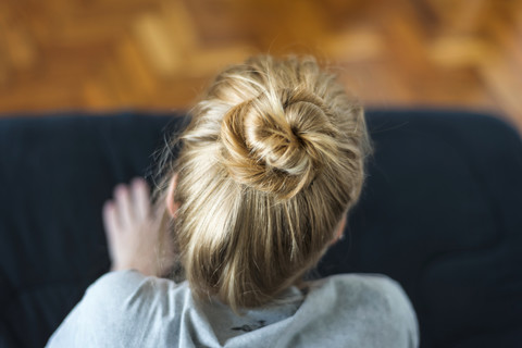 Woman with ginger hair bun sitting on sofa stock photo